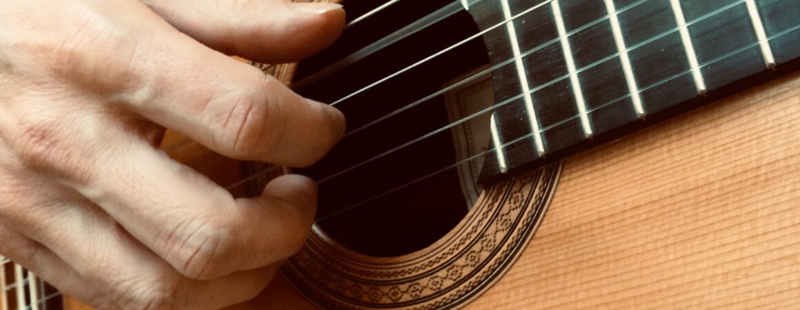 akustinen kitara ja soittava käsi